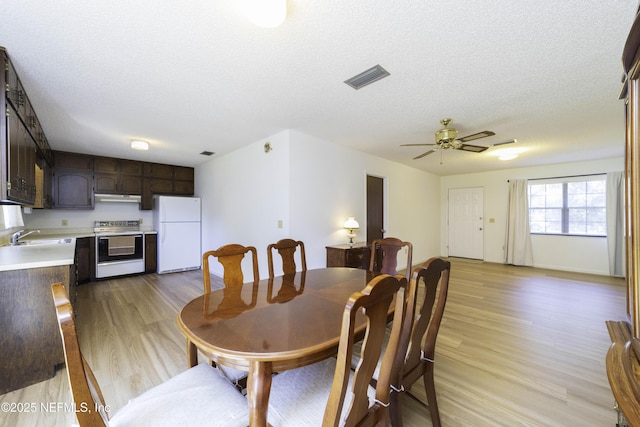 dining space featuring ceiling fan, visible vents, a textured ceiling, and light wood-style flooring