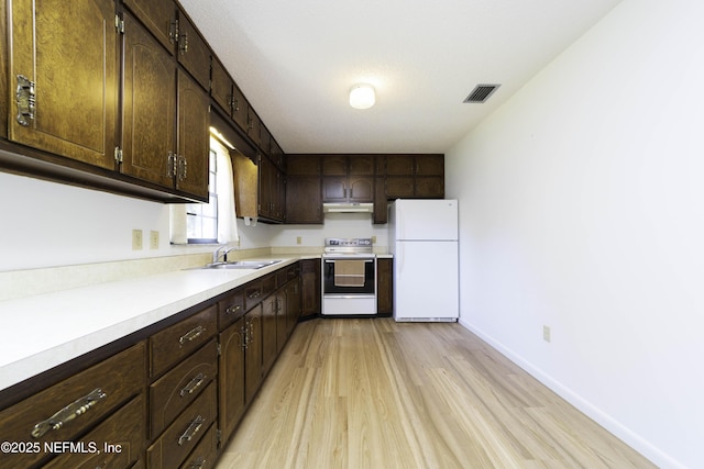 kitchen with white appliances, dark brown cabinets, under cabinet range hood, and a sink