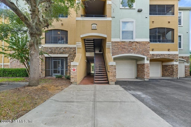 view of property with an attached garage, driveway, and stairway