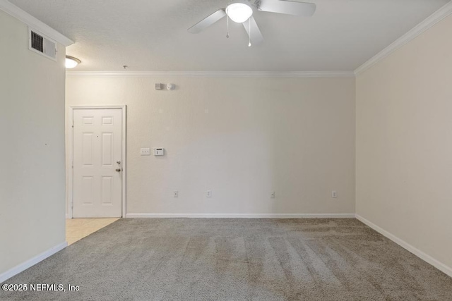 carpeted spare room featuring a ceiling fan, baseboards, visible vents, and crown molding