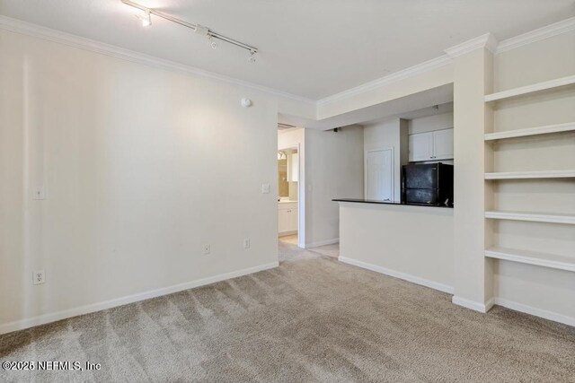 unfurnished living room with light carpet, rail lighting, baseboards, and crown molding