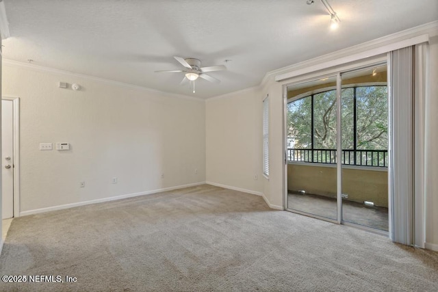 spare room with baseboards, a ceiling fan, rail lighting, crown molding, and carpet floors