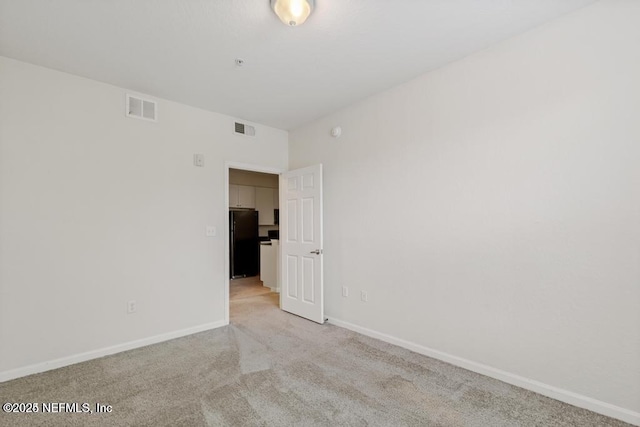 carpeted spare room featuring visible vents and baseboards