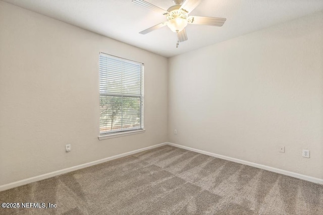 carpeted empty room featuring ceiling fan and baseboards