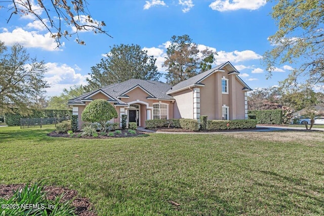 traditional-style home with a front yard, fence, and stucco siding