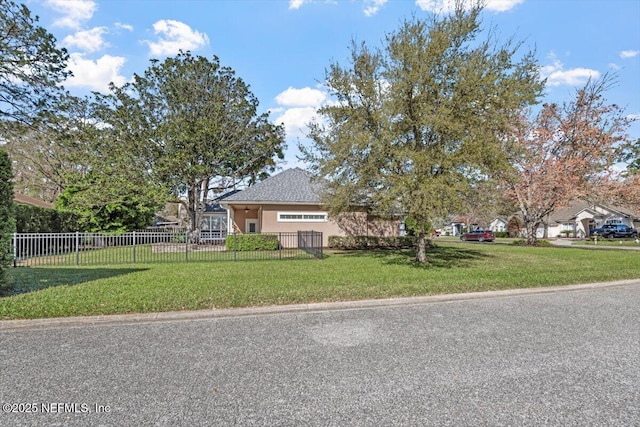 view of front of home with a fenced front yard, a front lawn, and stucco siding