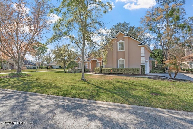 view of front of property featuring driveway, a front lawn, and stucco siding