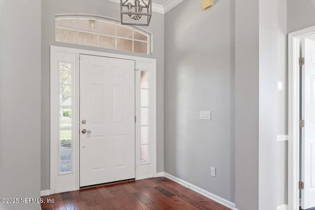 foyer featuring ornamental molding, dark wood-style flooring, a chandelier, and baseboards