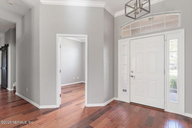 entrance foyer featuring an inviting chandelier, baseboards, ornamental molding, and hardwood / wood-style floors