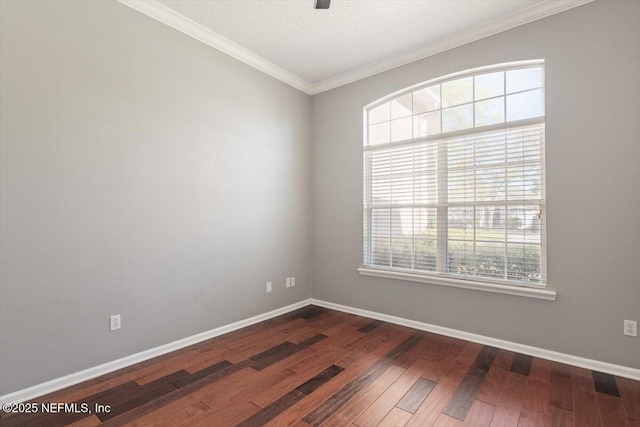 empty room featuring dark wood-style flooring, crown molding, and baseboards