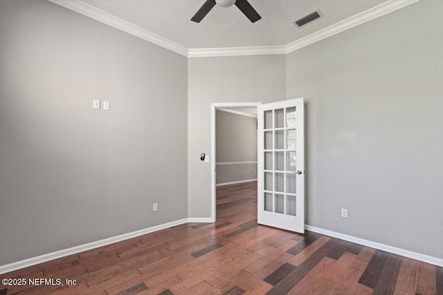 empty room with a textured ceiling, wood finished floors, a ceiling fan, visible vents, and crown molding