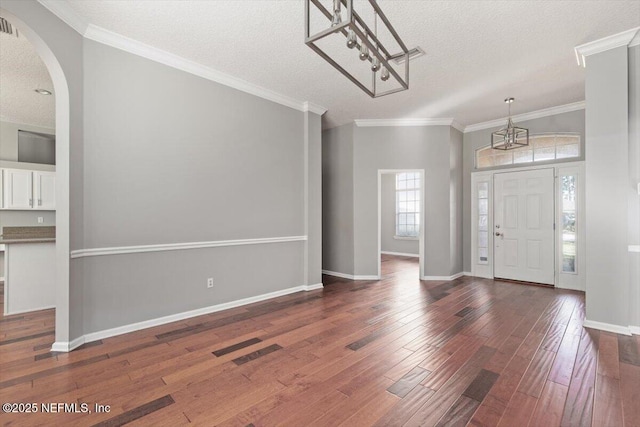 foyer entrance with a textured ceiling, ornamental molding, and wood-type flooring