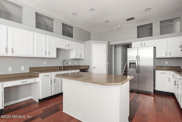 kitchen with visible vents, a sink, stainless steel refrigerator with ice dispenser, and white cabinetry