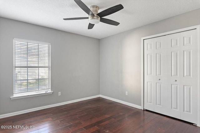 unfurnished bedroom with a textured ceiling, a closet, baseboards, and dark wood-type flooring