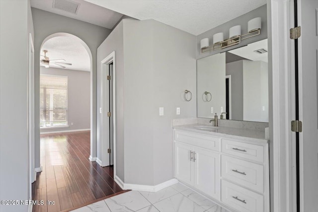 bathroom featuring visible vents, ceiling fan, vanity, a textured ceiling, and baseboards