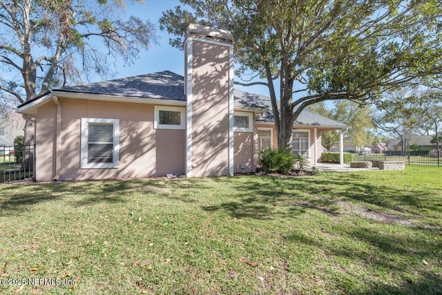 view of home's exterior with a lawn, fence, and stucco siding