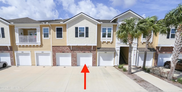 view of property featuring a garage, brick siding, driveway, and stairway