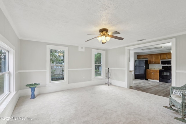 unfurnished living room with light carpet, visible vents, a ceiling fan, crown molding, and a textured ceiling