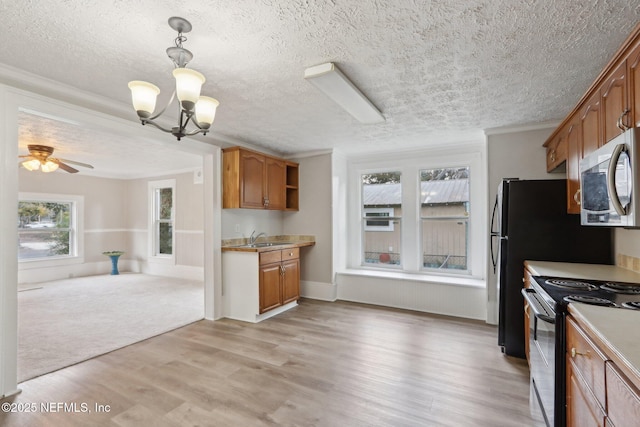 kitchen featuring stainless steel microwave, light countertops, light wood-style floors, a sink, and range with electric stovetop