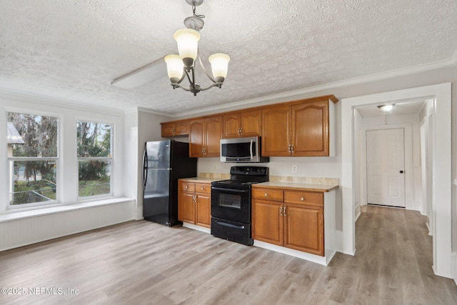 kitchen featuring light countertops, brown cabinets, light wood-style flooring, and black appliances