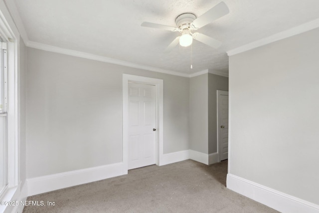 carpeted spare room with ceiling fan, baseboards, and ornamental molding