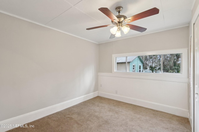 carpeted spare room with ceiling fan and baseboards