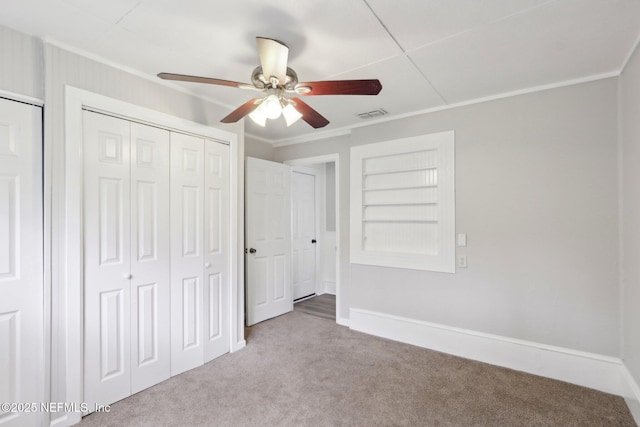 unfurnished bedroom with ornamental molding, visible vents, carpet floors, and baseboards