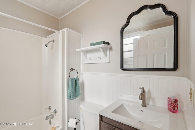 full bath featuring wainscoting, toilet, shower / tub combination, a textured ceiling, and vanity