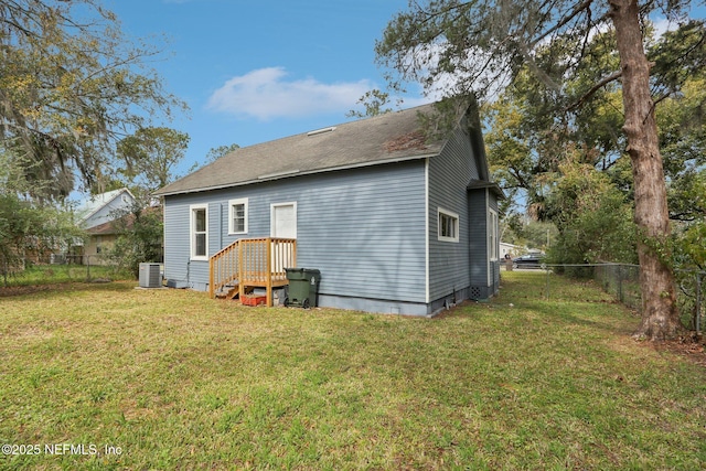 back of property featuring a lawn, cooling unit, and fence