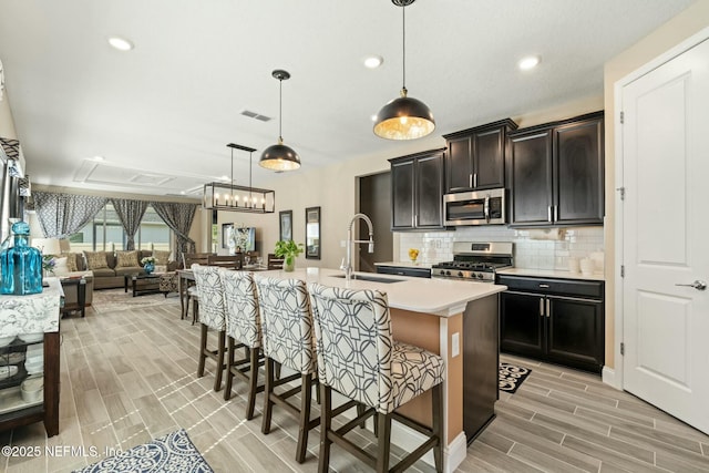 kitchen featuring tasteful backsplash, visible vents, appliances with stainless steel finishes, open floor plan, and a breakfast bar area