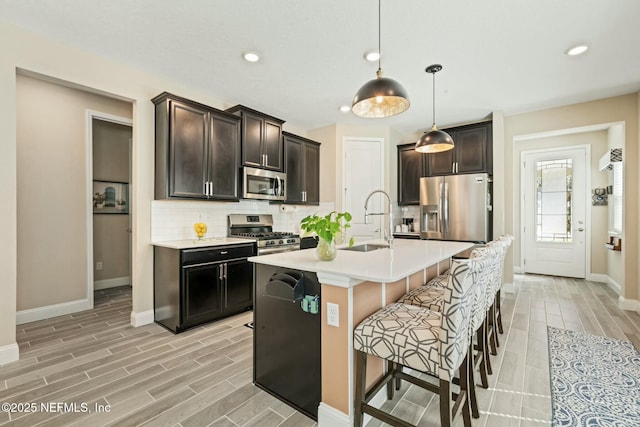 kitchen featuring tasteful backsplash, wood tiled floor, stainless steel appliances, and a sink