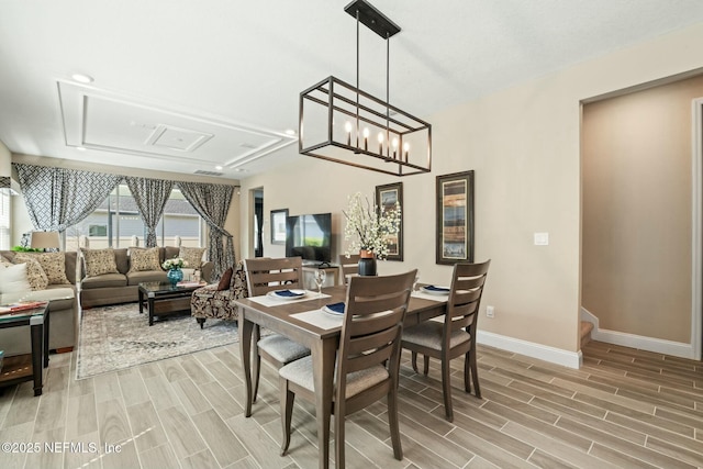 dining area with wood tiled floor, stairs, baseboards, and a chandelier