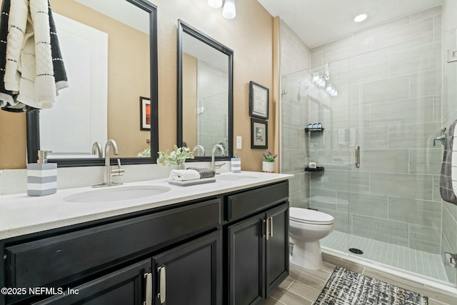 bathroom with double vanity, a stall shower, a sink, and toilet