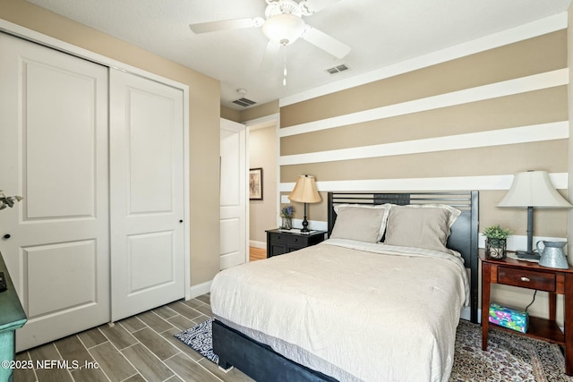 bedroom featuring baseboards, wood tiled floor, visible vents, and a closet