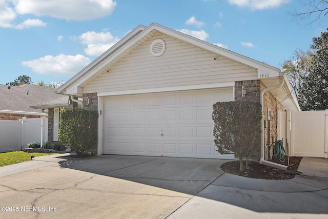 garage with a gate, concrete driveway, and fence