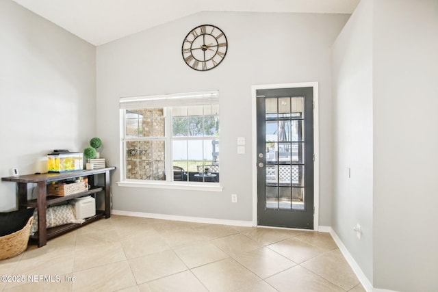 doorway to outside featuring vaulted ceiling, light tile patterned floors, and baseboards