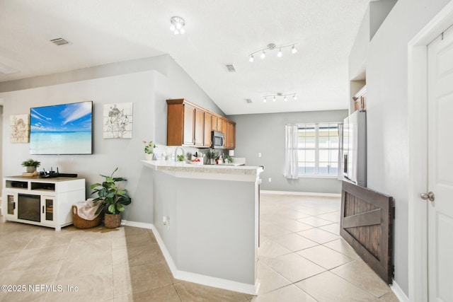 kitchen featuring visible vents, brown cabinets, stainless steel microwave, light countertops, and light tile patterned floors