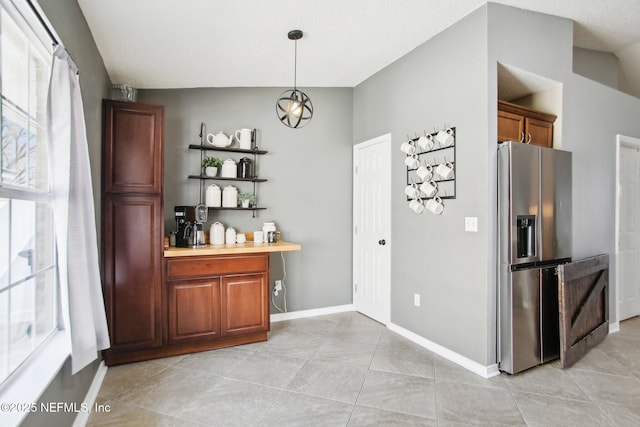 kitchen featuring light tile patterned floors, baseboards, stainless steel fridge, and pendant lighting