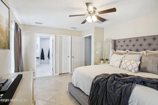 bedroom featuring light tile patterned floors, visible vents, ensuite bath, ceiling fan, and a textured ceiling