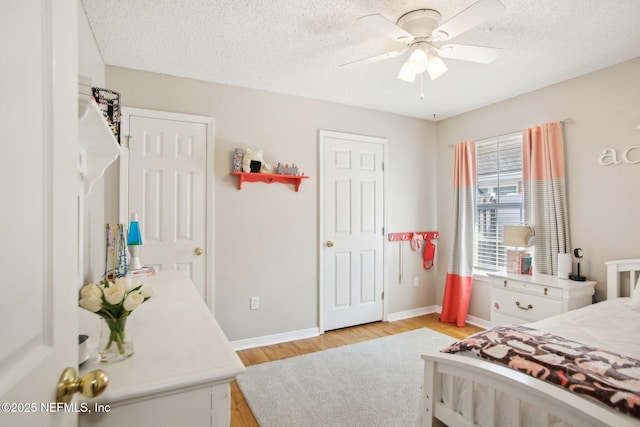 bedroom with a ceiling fan, baseboards, light wood-type flooring, and a textured ceiling