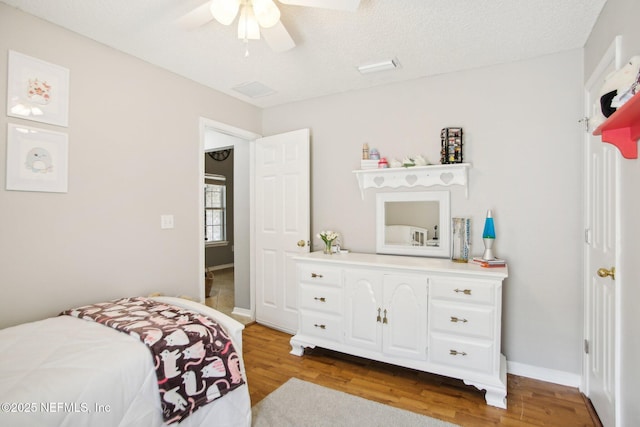 bedroom with a textured ceiling, wood finished floors, and a ceiling fan