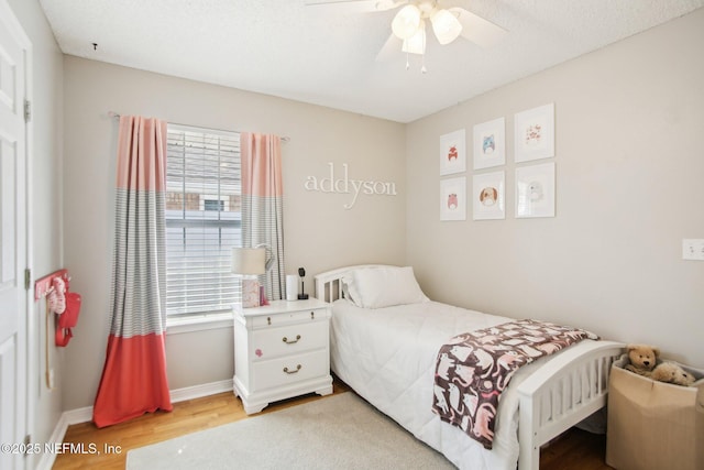 bedroom with baseboards, multiple windows, light wood-style floors, and ceiling fan