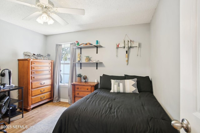 bedroom with a textured ceiling, ceiling fan, and light wood finished floors