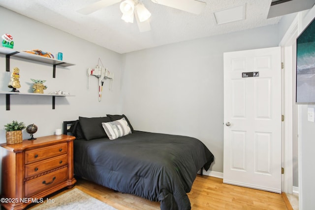 bedroom featuring baseboards, visible vents, light wood-style flooring, ceiling fan, and a textured ceiling