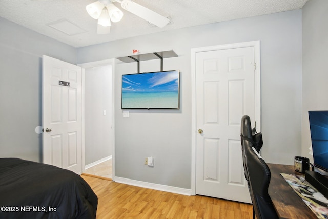 bedroom with a ceiling fan, baseboards, light wood finished floors, and a textured ceiling