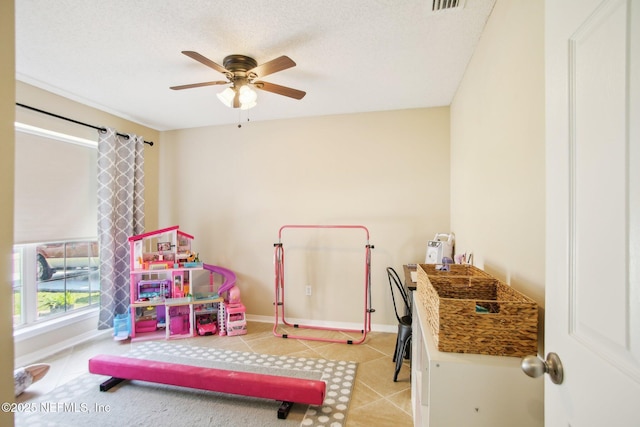 recreation room with tile patterned floors, visible vents, a textured ceiling, baseboards, and ceiling fan