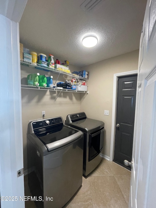 laundry room featuring light tile patterned flooring, laundry area, washer and dryer, and a textured ceiling