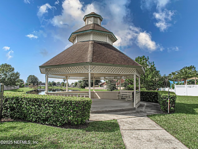 view of home's community with a gazebo, a lawn, fence, and a water view