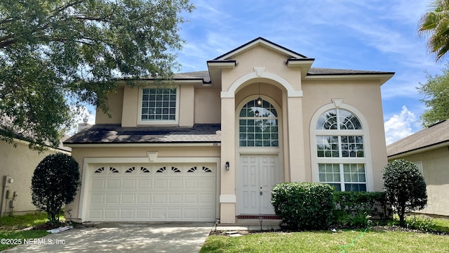 view of front of property with driveway, an attached garage, a shingled roof, and stucco siding