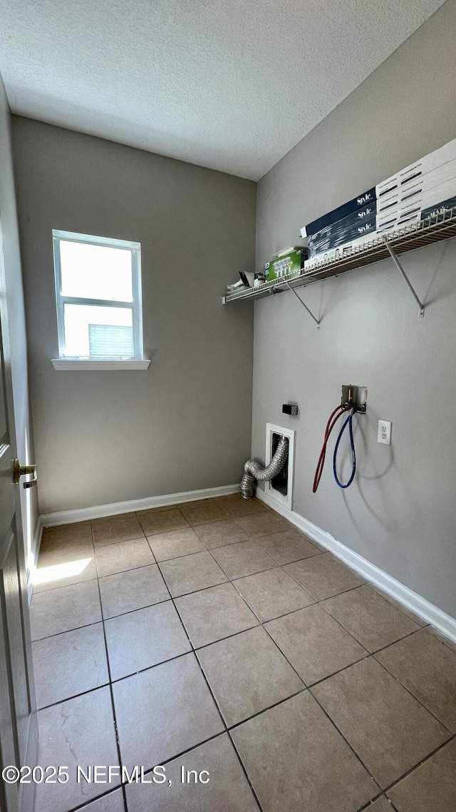 washroom with a textured ceiling, hookup for a washing machine, laundry area, baseboards, and tile patterned floors